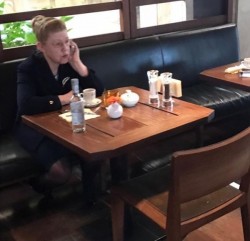 Женщина в кафе разговаривает по телефону, на столе напитки