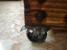 Деревянный предмет с металлическими колесиками на плиточном полу
